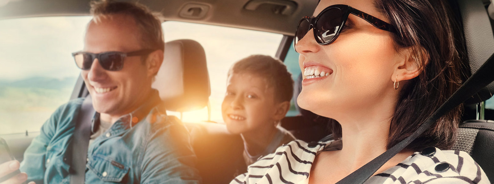 Family driving in a new car smiling.