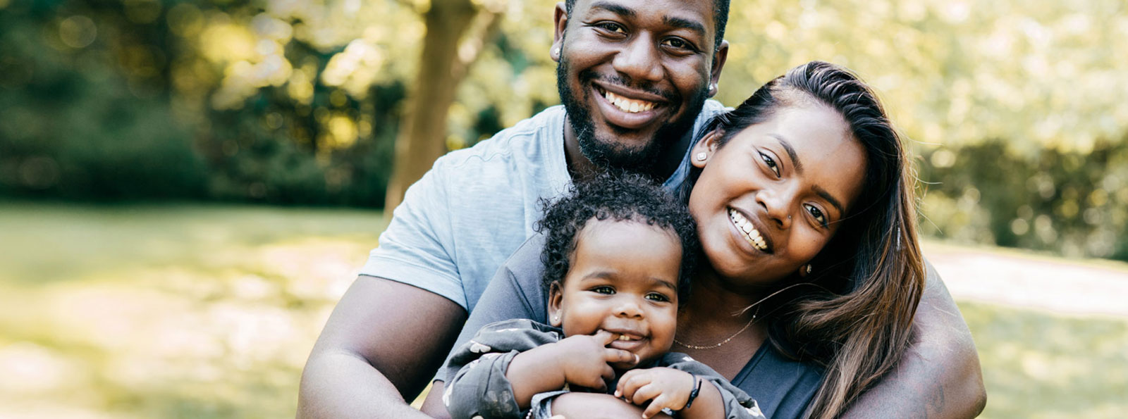 Family hugging and smiling outdoors.