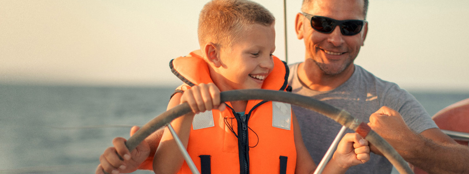 Father helping child drive a boat.
