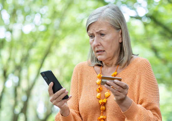 Worried woman holding phone and credit card