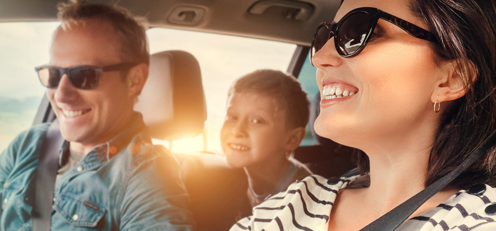 Family smiling and driving in new car.