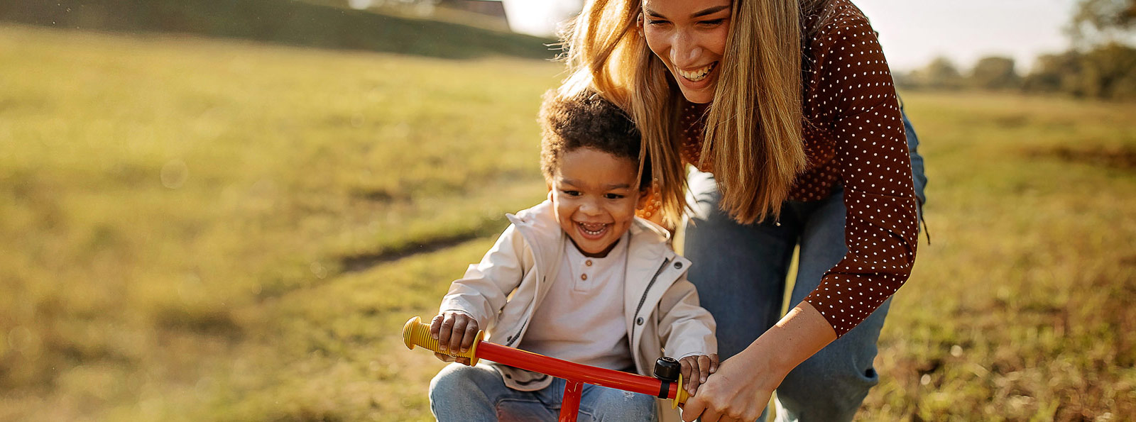 Mother pushing child on a tricycle.